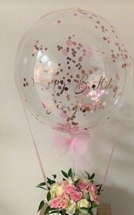 Confetti Transparent bobo balloon with print happy birthday tied to a basket with 12 pink and white roses with pink ribbons