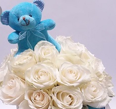 Blue 6 inches Teddy bear in a basket of 15 white roses